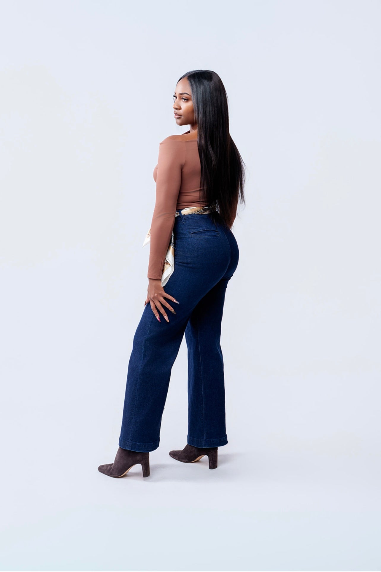 Woman wearing blue high-waisted jeans on a white background