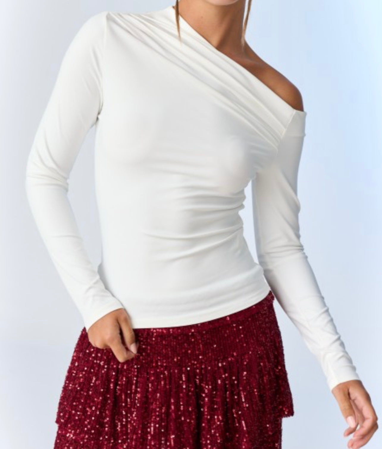 White long-sleeve off the shoulder top worn by a person on a light gray background