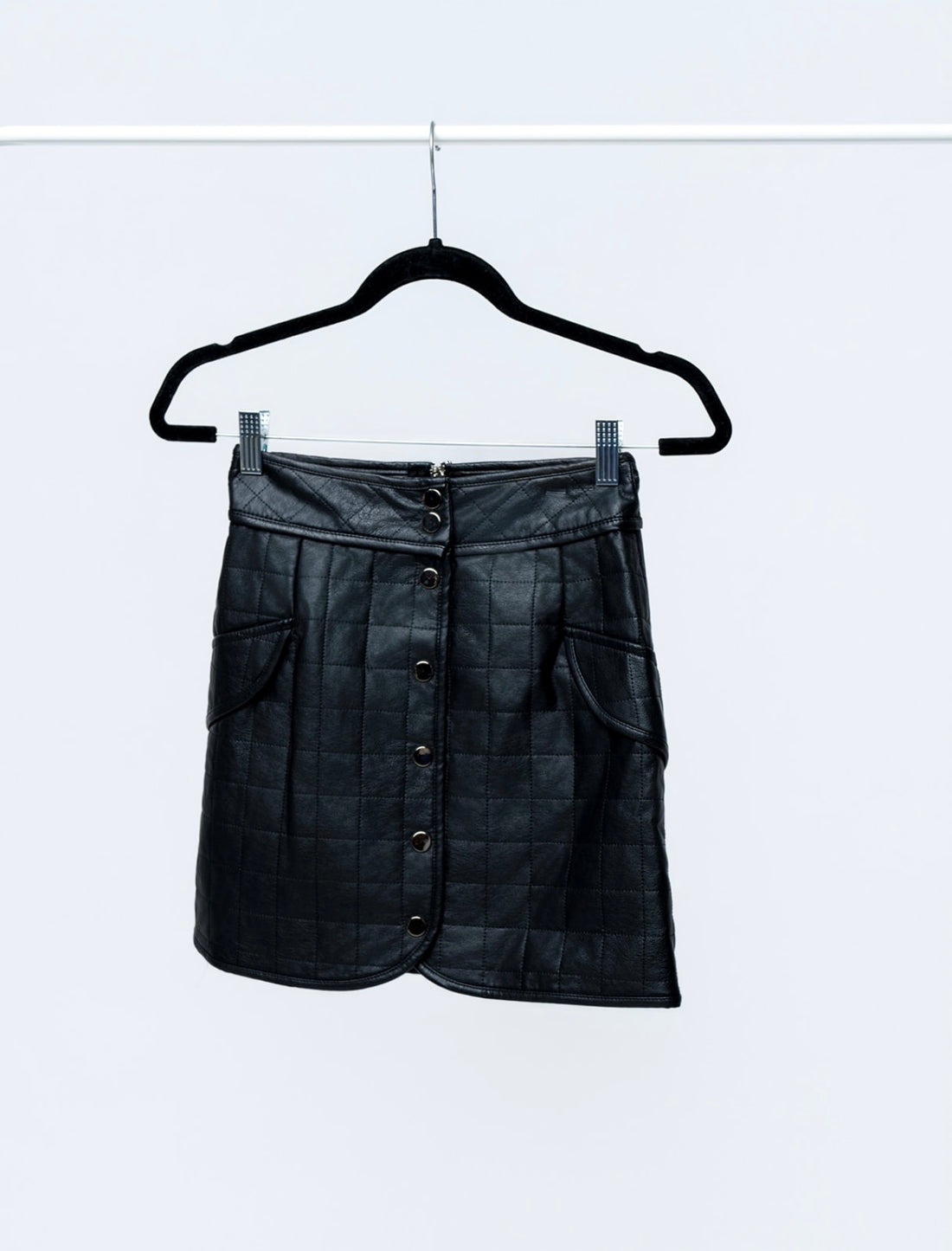 Black leather skirt on a hanger against a white background