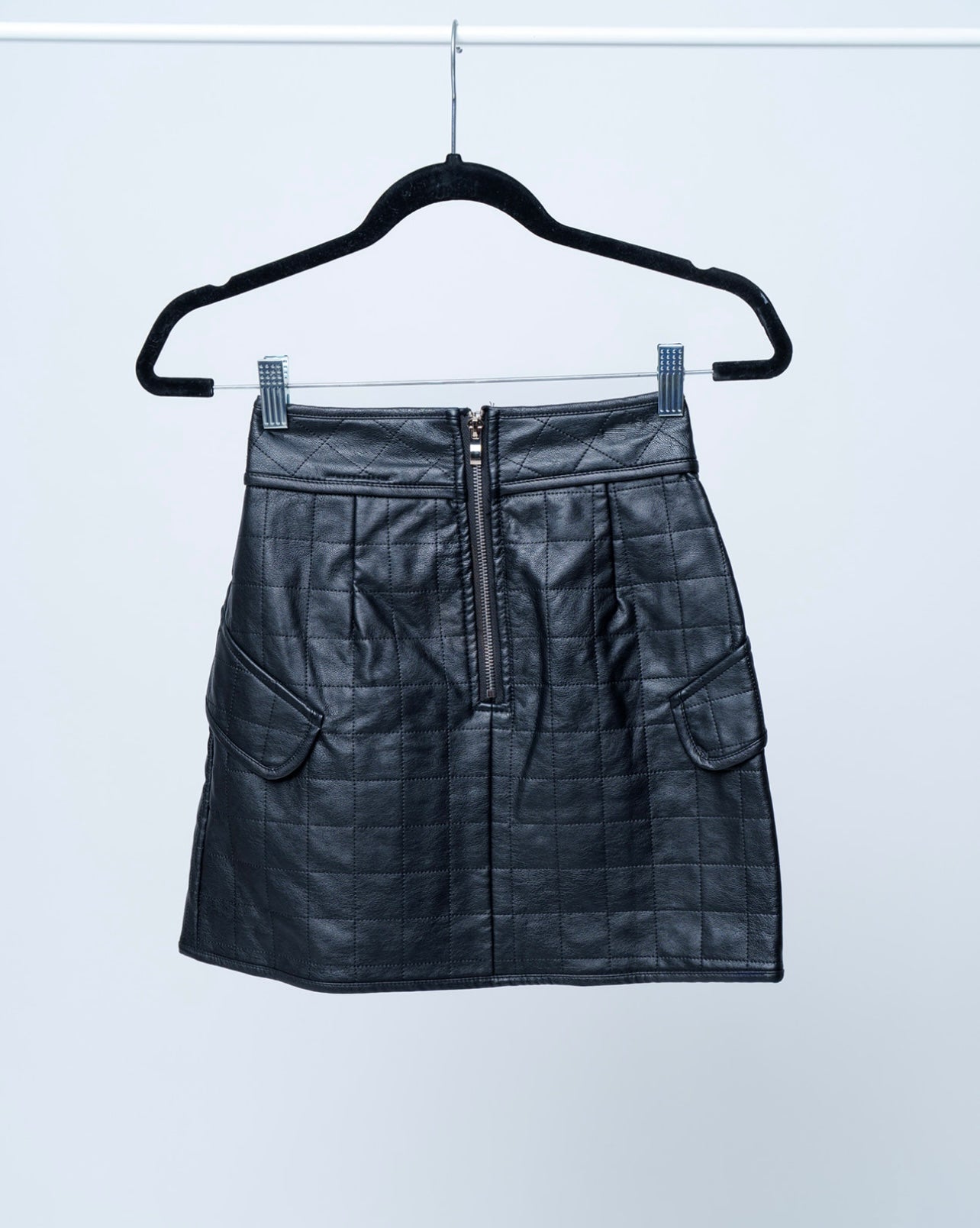 Black leather skirt on a hanger against a white background