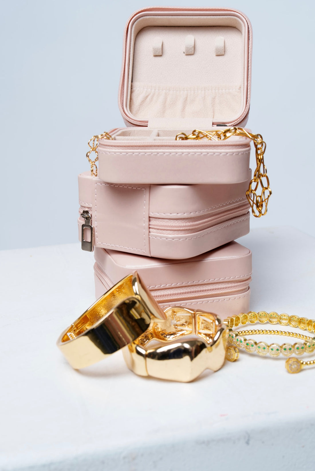 Stack of pink travel compact jewelry boxes with jewelry