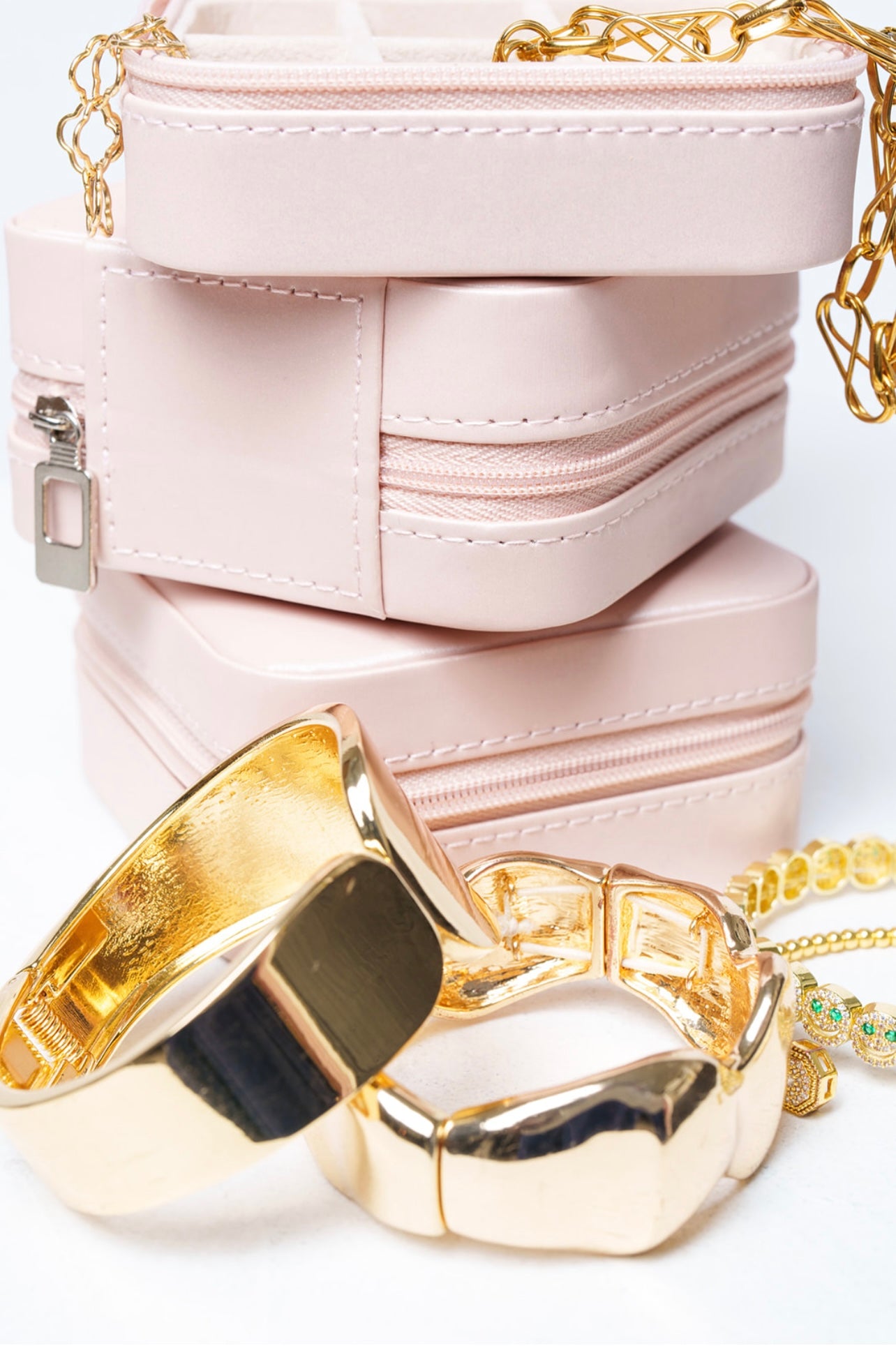 Stack of pink jewelry boxes with jewelry on a white background