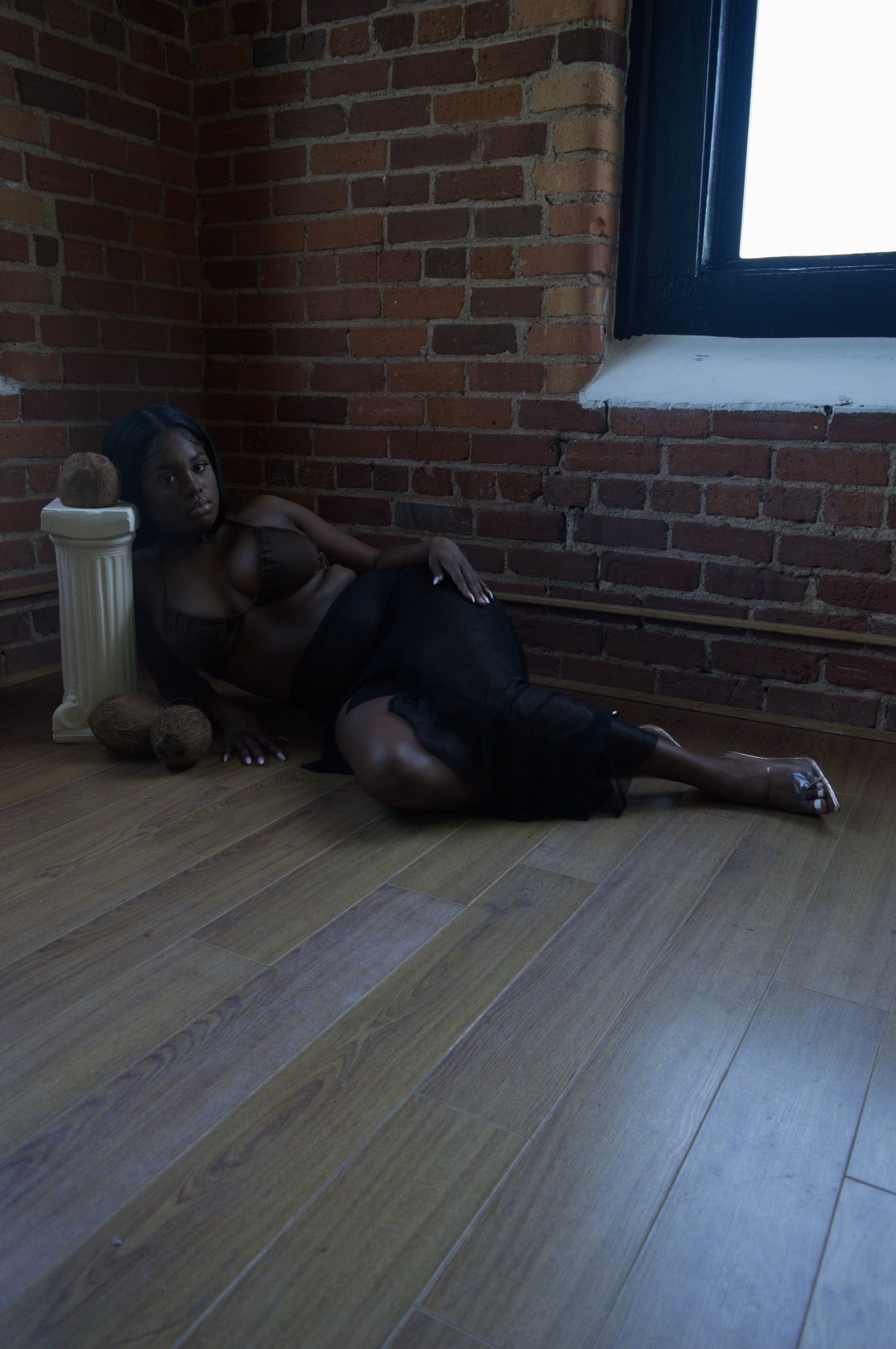 woman wearing a sheer black maxi skirt laying on a wood floor
