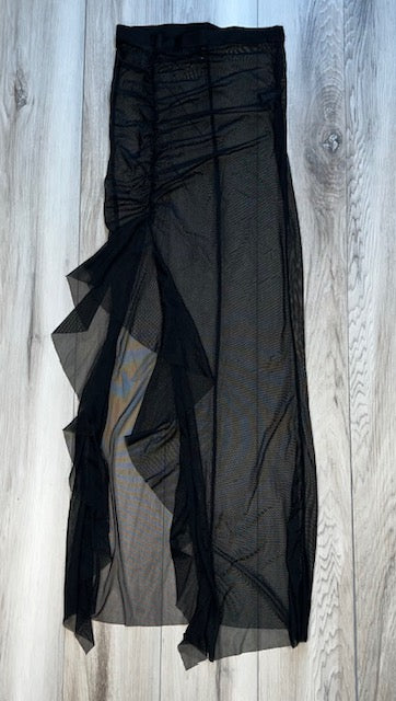 A black skirt with slit, ruffle, and ruched embellishments displayed against a wooden background.