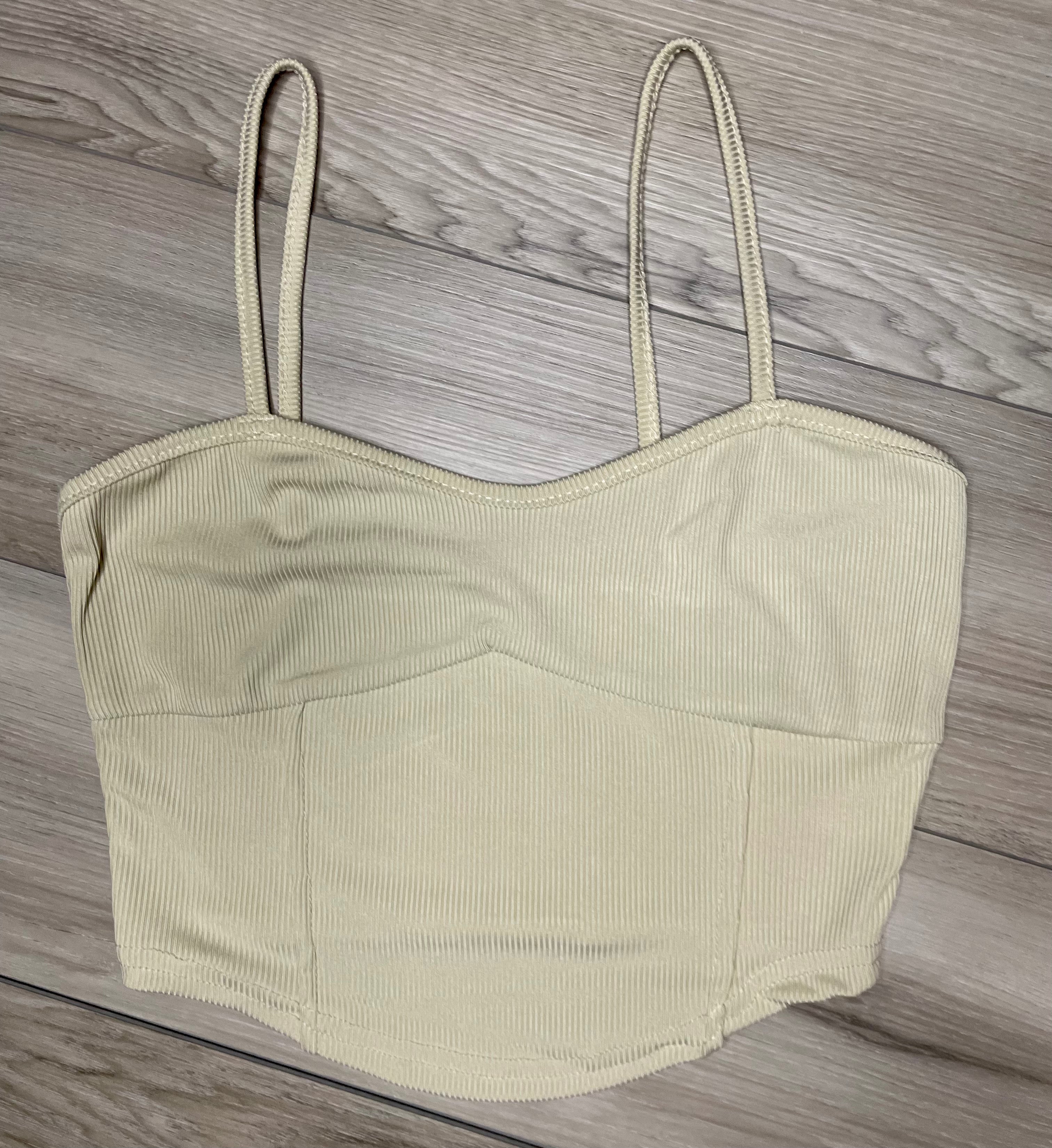 cream cropped tank top with ribbed texture  against a neutral wooden background flat. lay