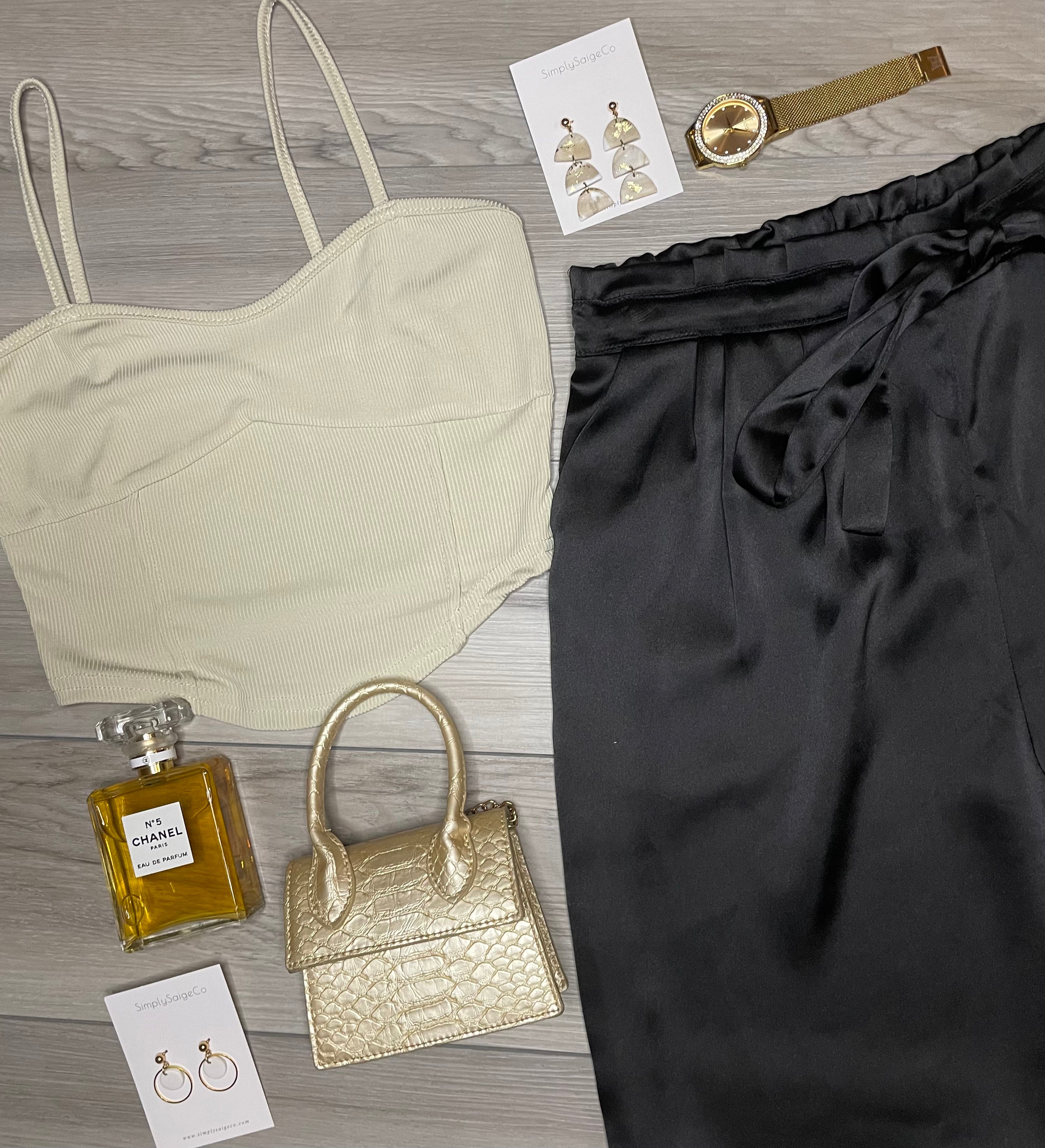 A set of beige and gold colored rib knitted halter vest tops with matching rib knitted pants, a gold watch, and a gold purse, displayed on a flat surface.