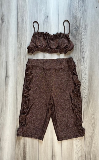A brown, sparkly, lycra/spandex dance dress pants with a V-neck top, laid out flat on a wooden surface.