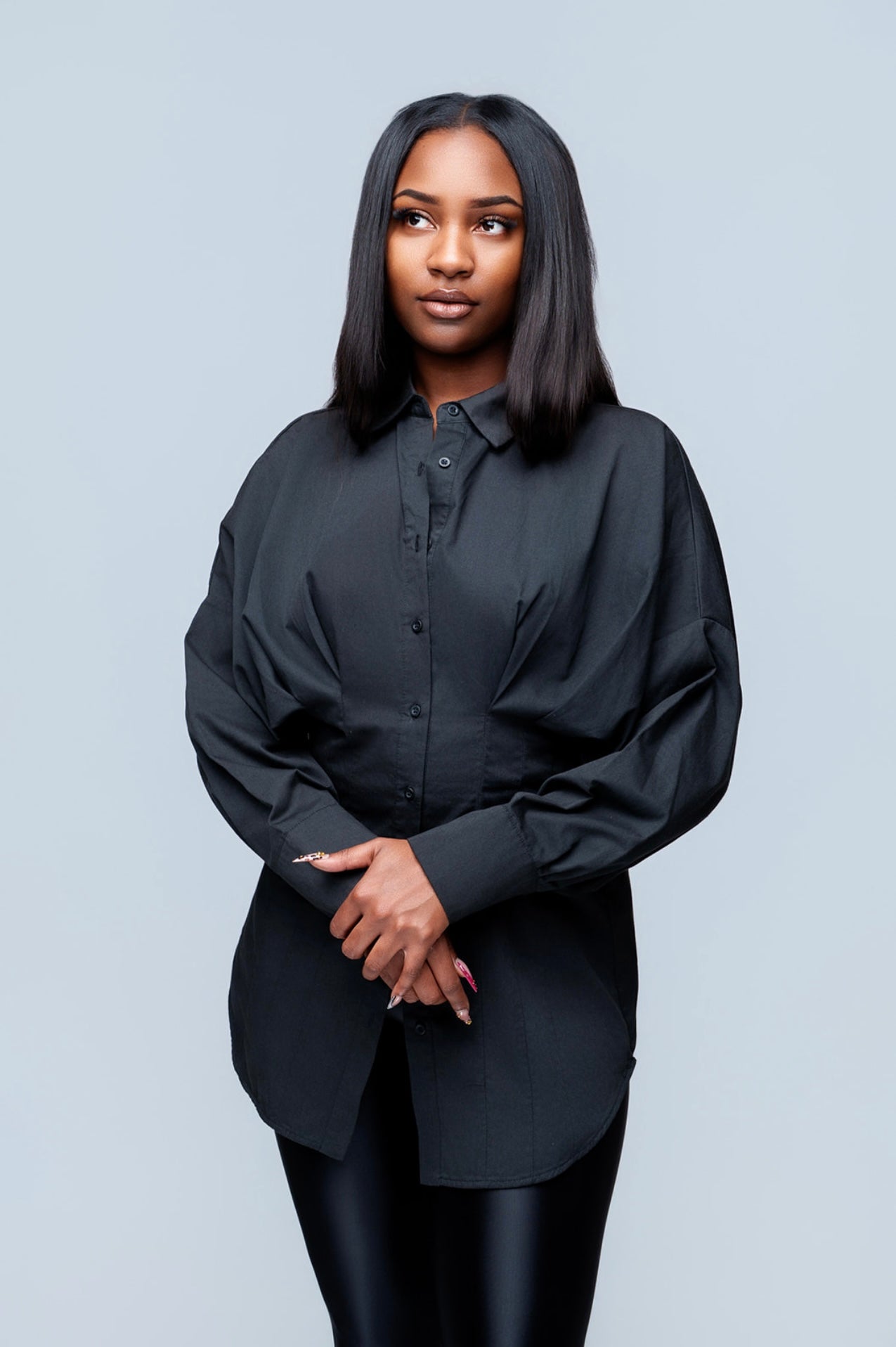 Woman wearing a black button up shirt against a light gray background