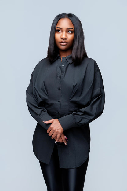 Woman wearing a black button up shirt against a light gray background