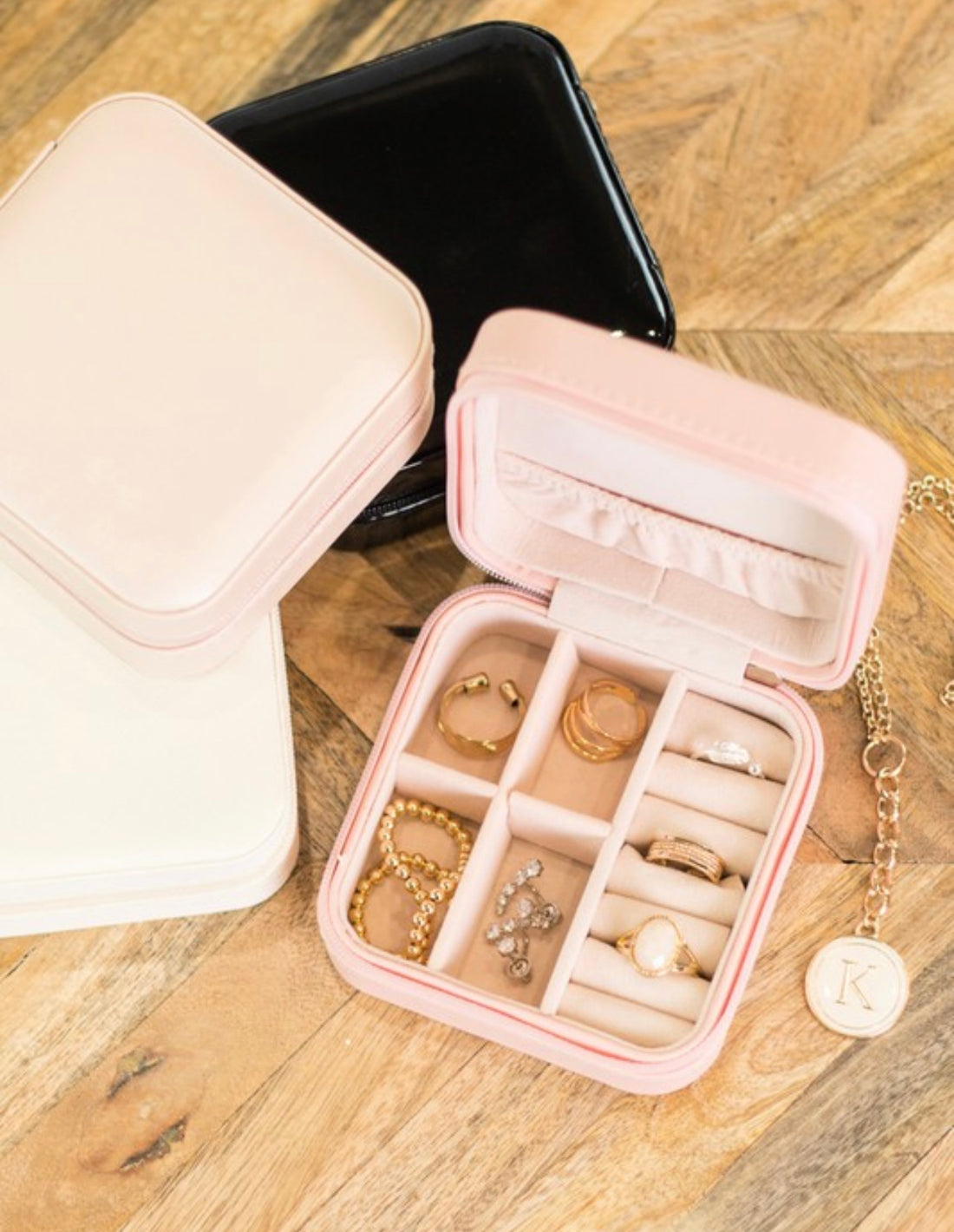 Travel jewelry case with compartments filled with rings and a necklace on a wooden surface