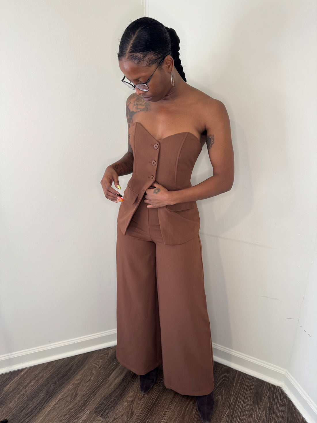 Person wearing a brown matching set standing against a white wall.
