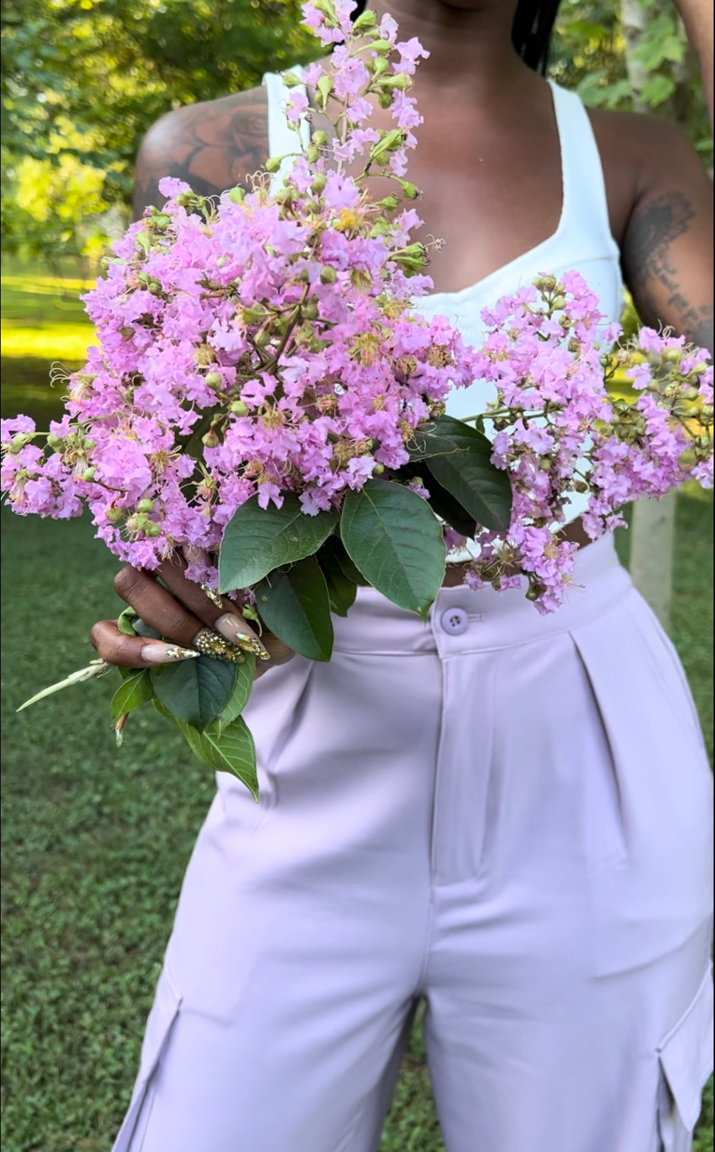 Photo of woman modeling lavender pleated trousers holding flowers