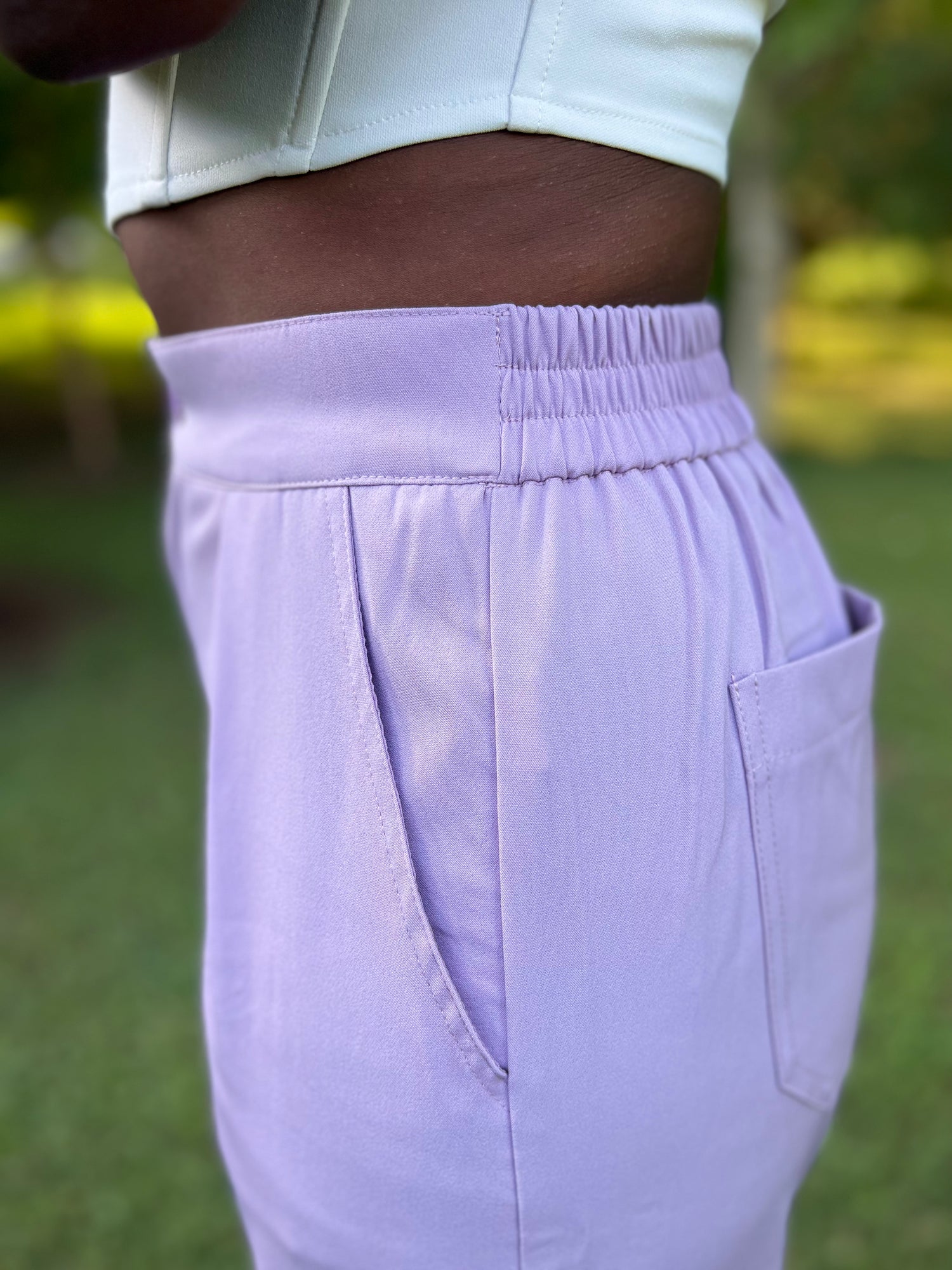 Photo of woman modeling lavender pleated trousers holding flowers