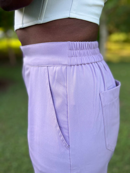 Photo of woman modeling lavender pleated trousers holding flowers