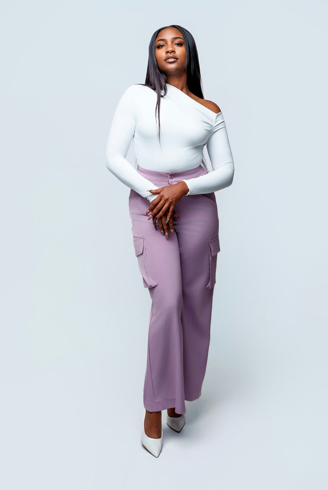 Woman wearing a white top and purple pants on a light gray background