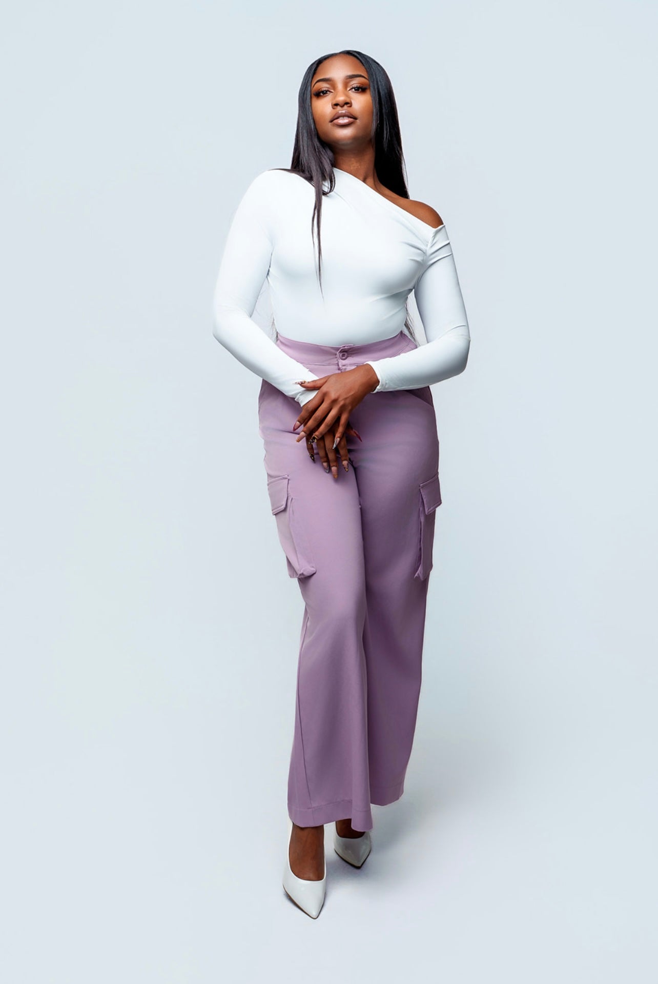 Woman wearing a white top and purple pants on a light gray background