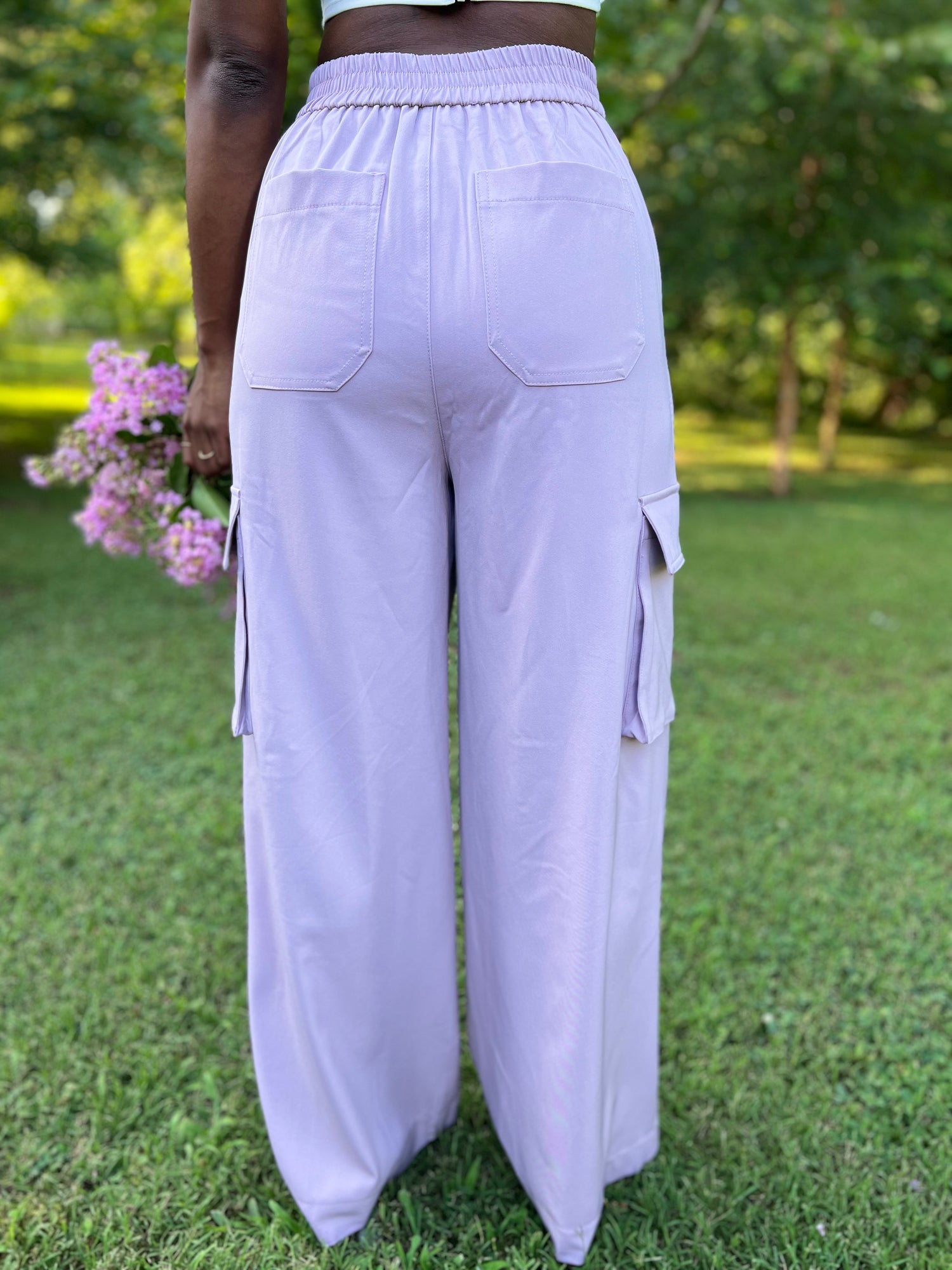 Photo of woman modeling lavender pleated trousers holding flowers