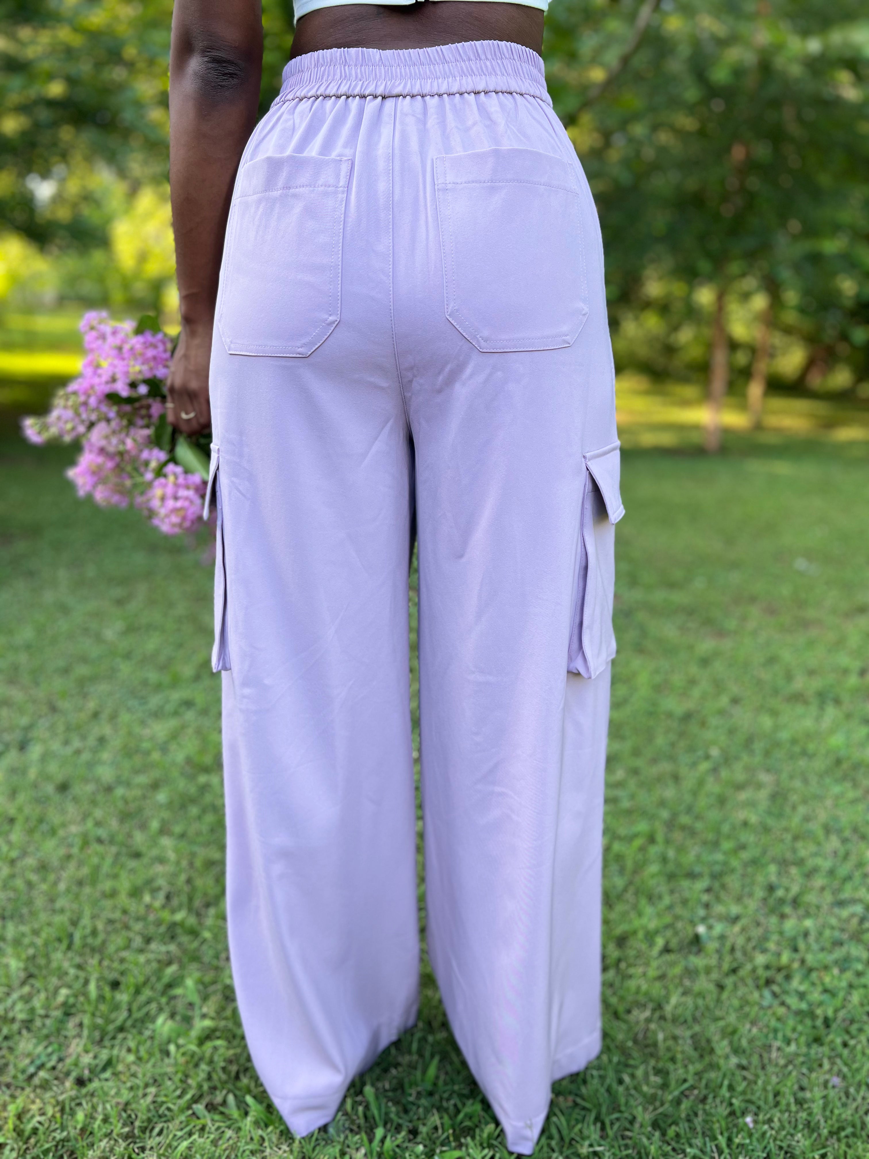 Photo of woman modeling lavender pleated trousers holding flowers
