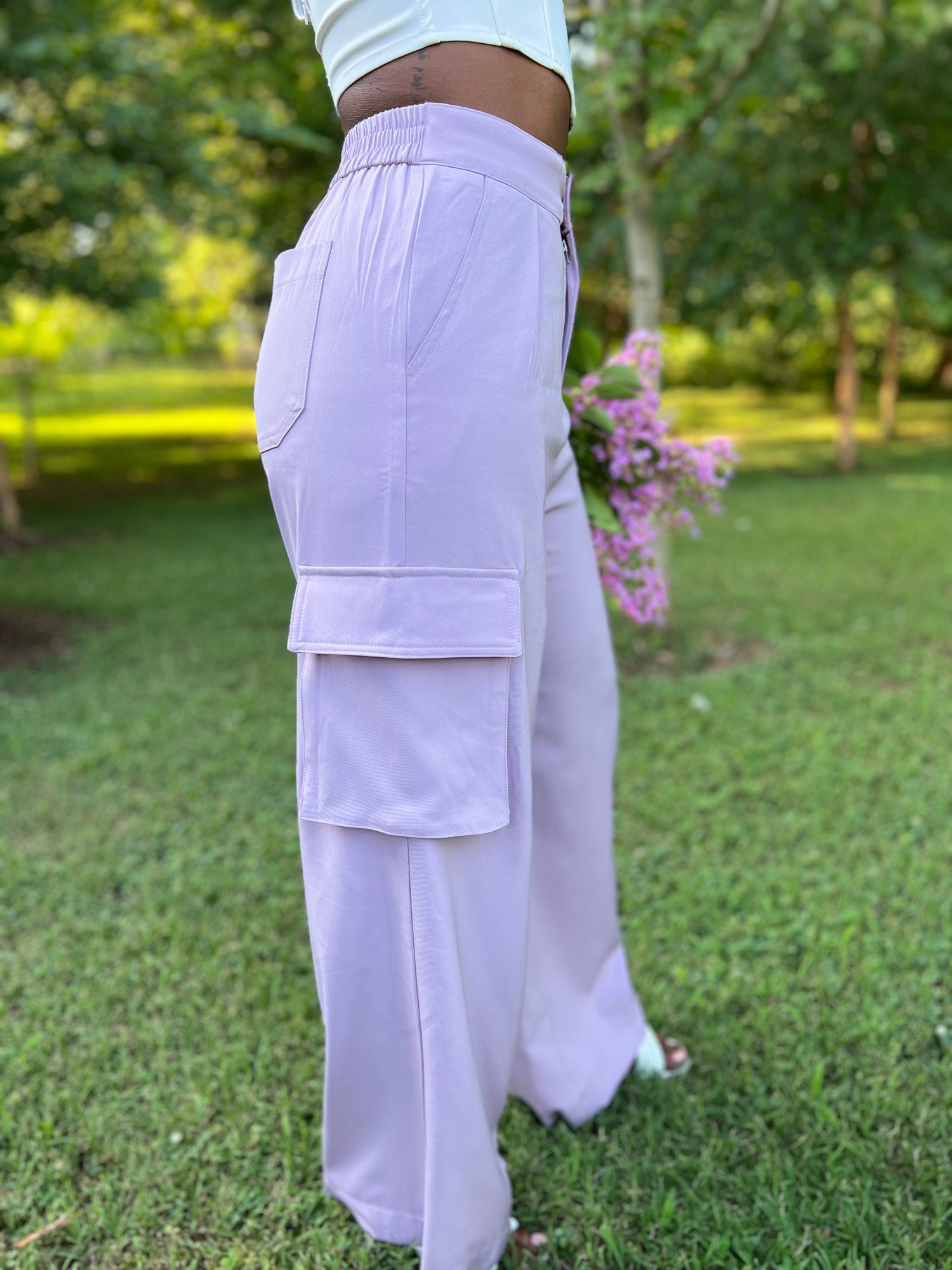 Photo of woman modeling lavender pleated trousers holding flowers