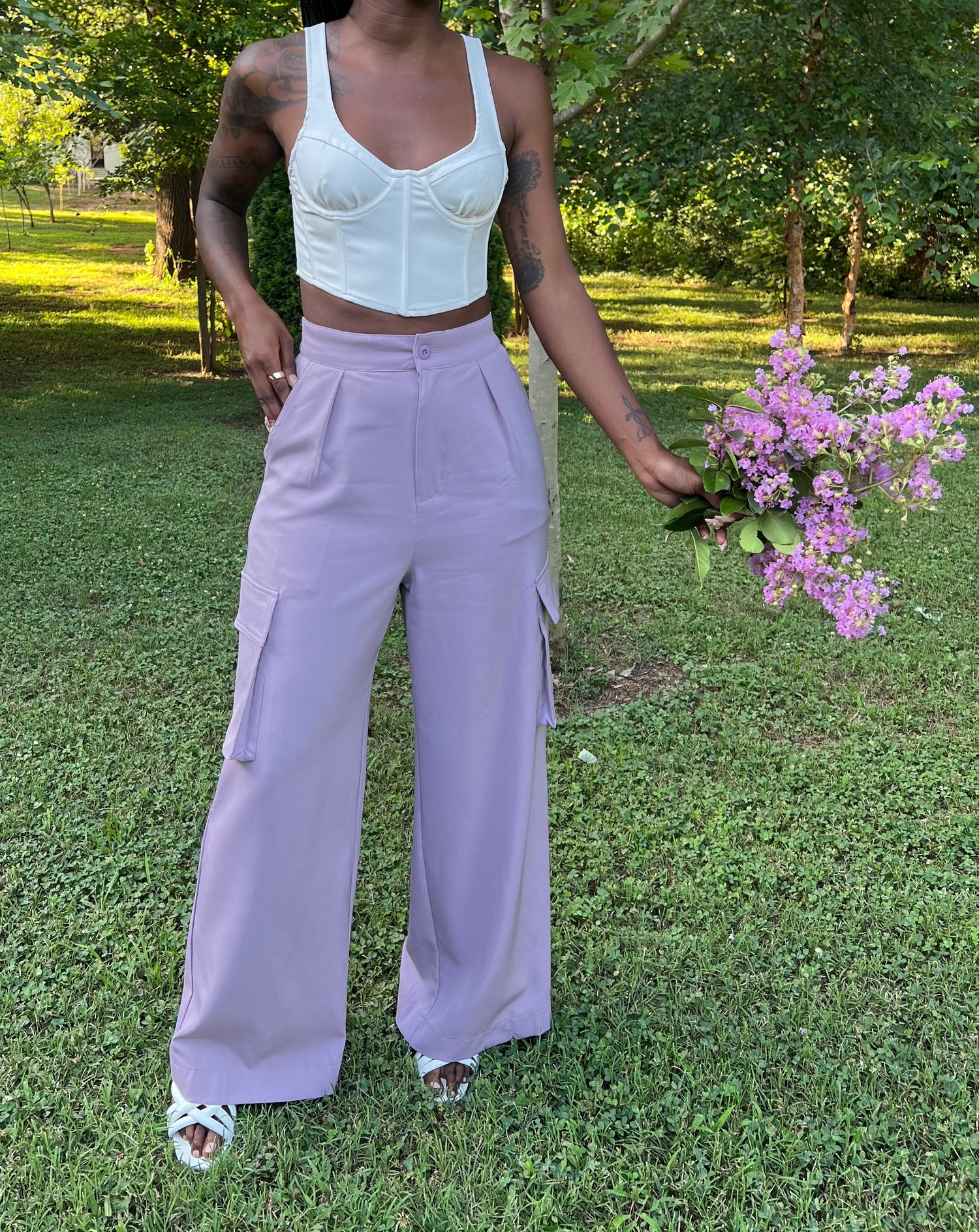 Photo of woman modeling lavender pleated trousers holding flowers