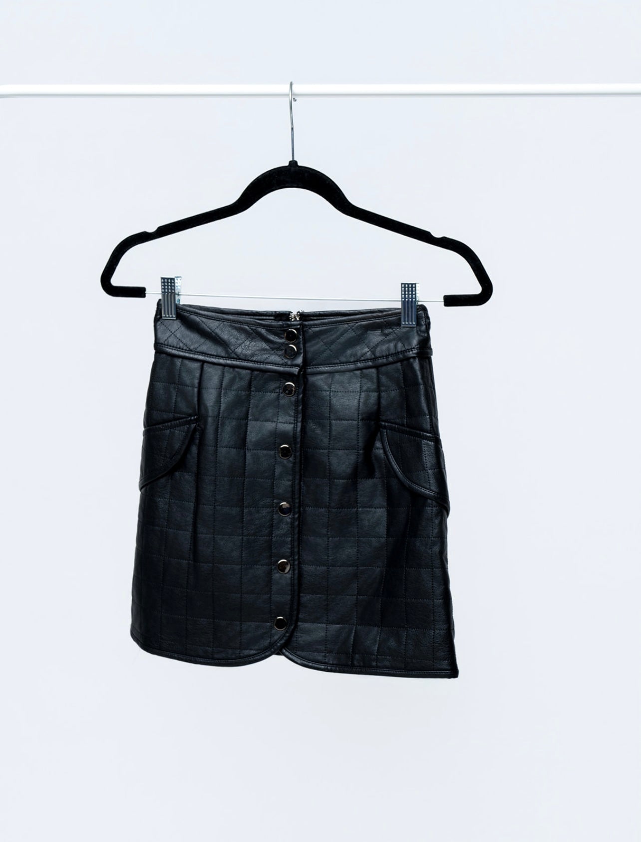 Black leather skirt on a hanger against a white background