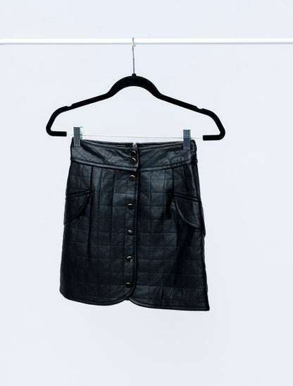 Black leather skirt on a hanger against a white background