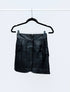 Black leather skirt on a hanger against a white background