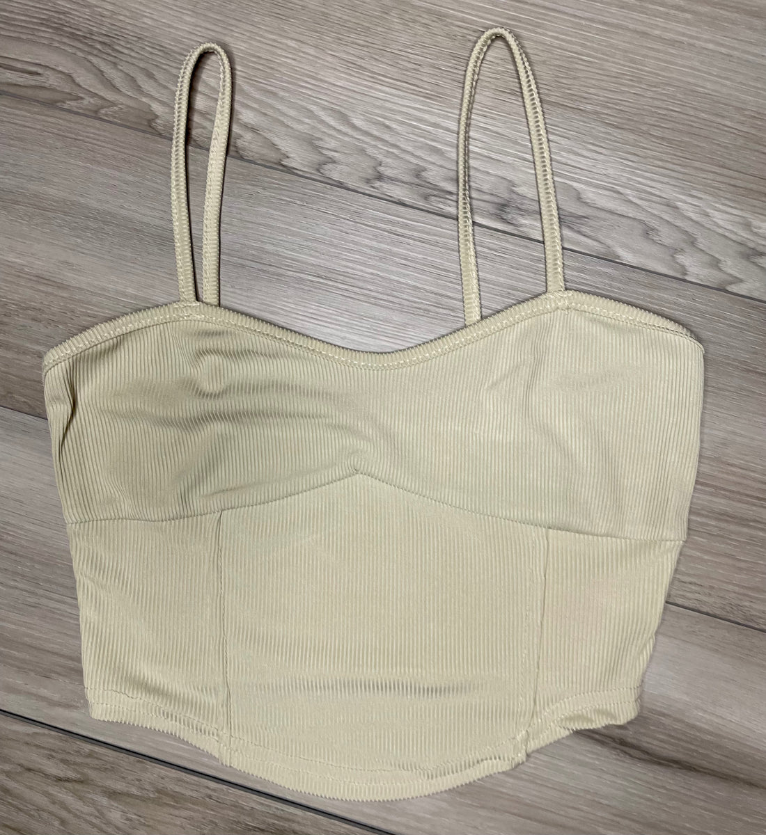 cream cropped tank top with ribbed texture  against a neutral wooden background flat. lay