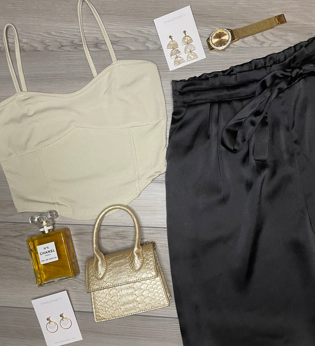 A set of beige and gold colored rib knitted halter vest tops with matching rib knitted pants, a gold watch, and a gold purse, displayed on a flat surface.