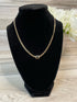 A gold-plated cuban link chain necklace with a black stone a lobster claw clasp, displayed on a mannequin.